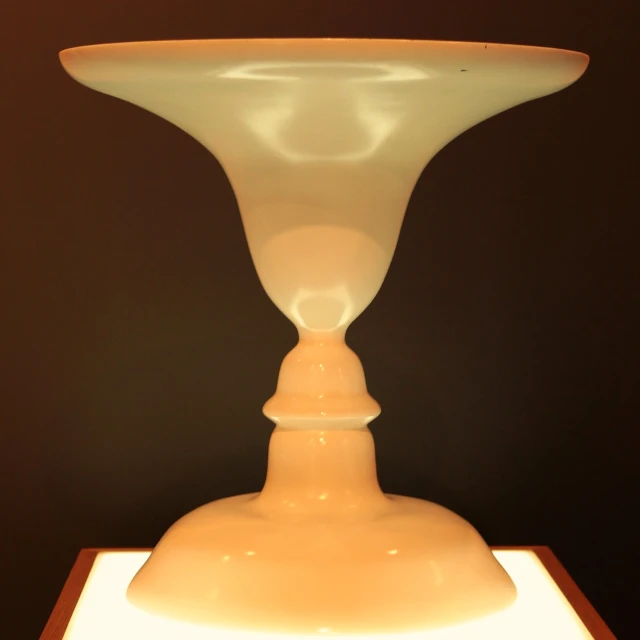 a white vase sitting on a white and wooden pedestal