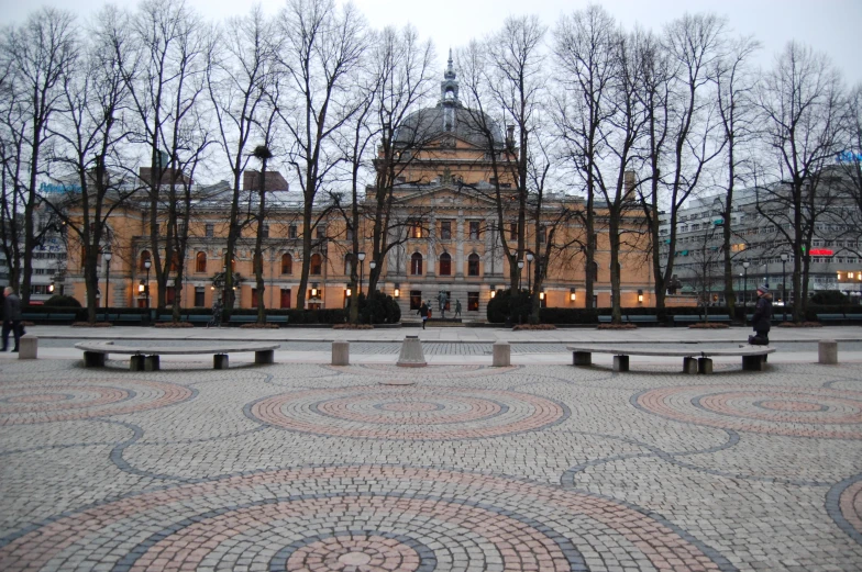 there are trees and stone benches in front of the building