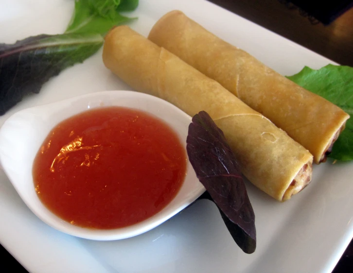 two rolls sitting on top of a plate next to a bowl of sauce