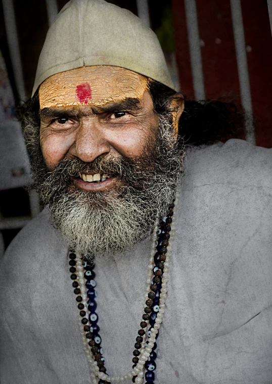 a man with a beard is smiling and wearing beaded necklaces