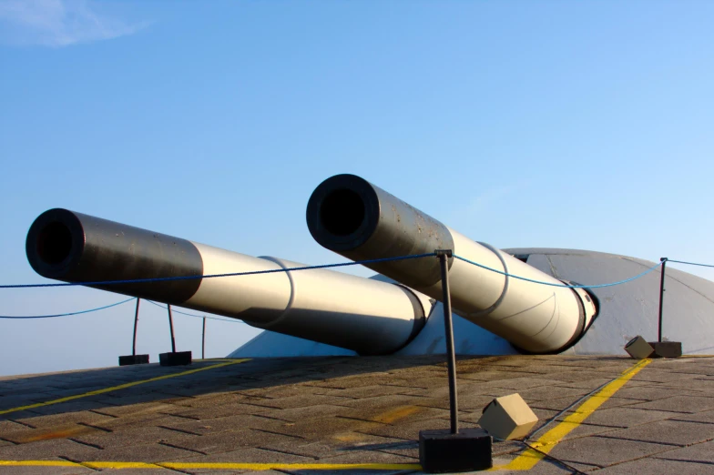 large metal pipes with black poles and yellow lines next to a building