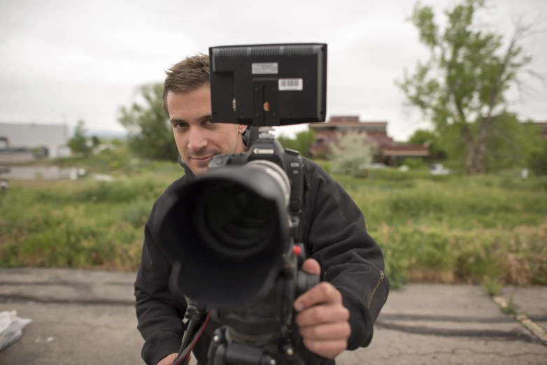 a man holding a camera looking through a window