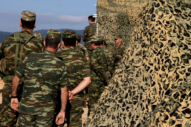 a group of soldiers stand next to a stone wall