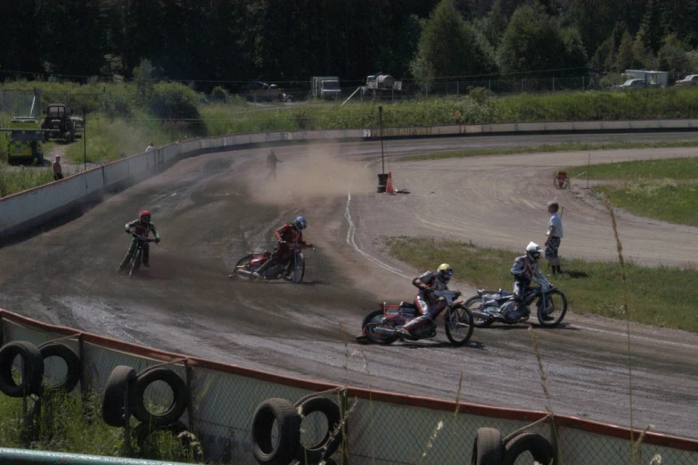 three men on motorcycles going around a track