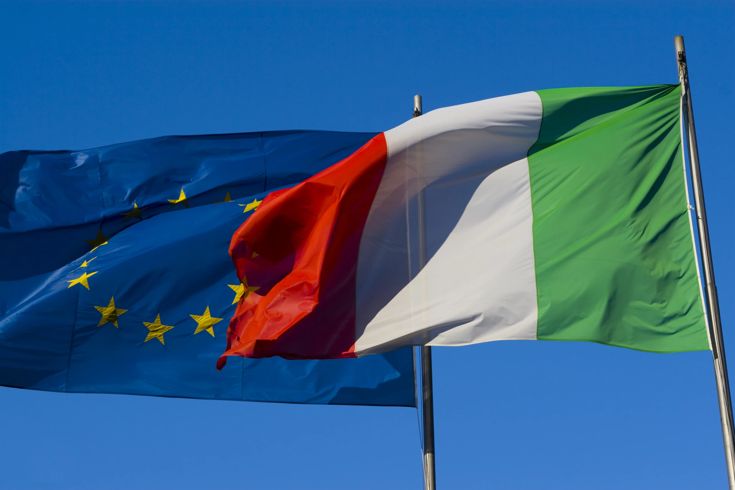 a pair of italian and green flags fly in the wind