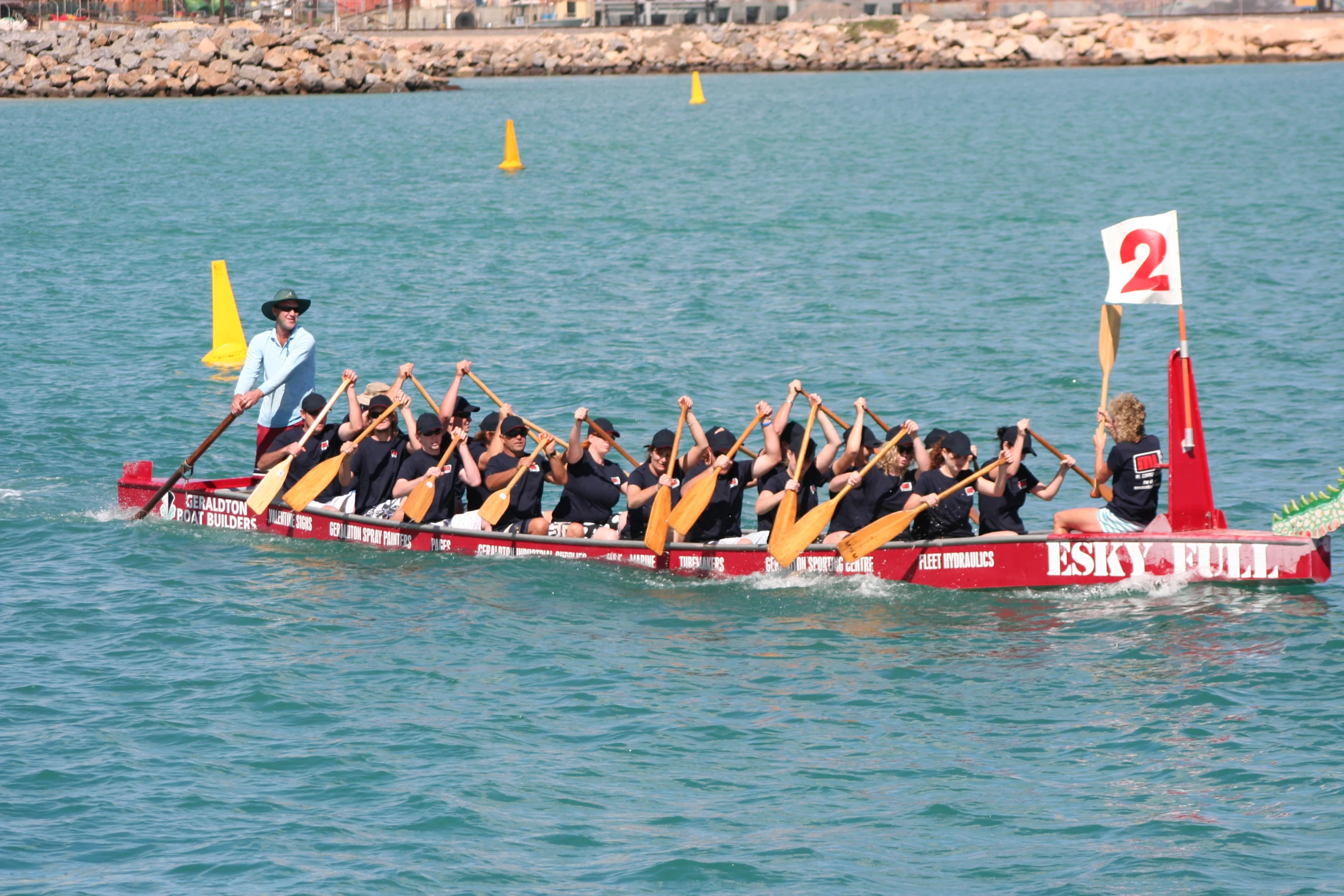 a team of people rowing a boat with a man sitting on the back row