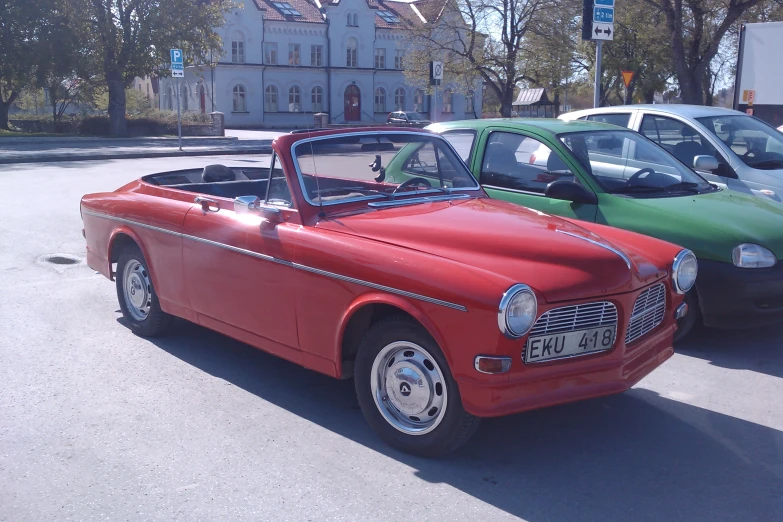 an old red car and green car in parking lot