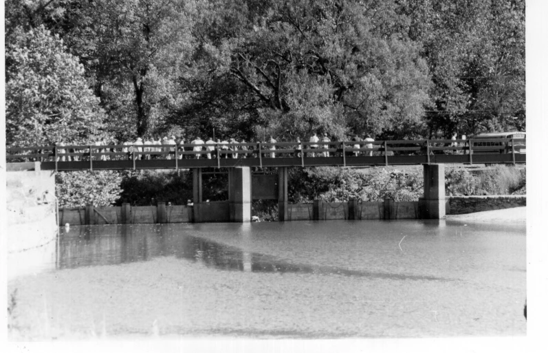 black and white po of people walking over a bridge