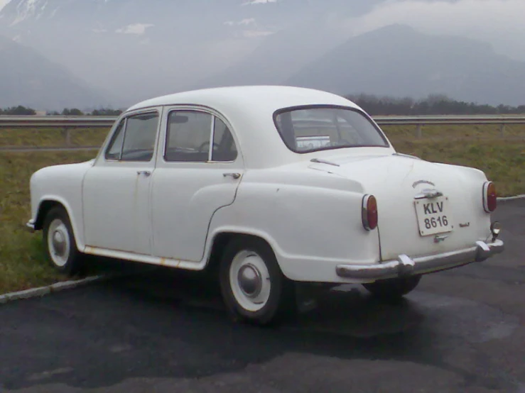 an old white car is parked in a parking lot