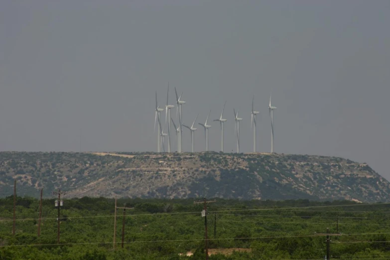 an area with a mountain, fenced in and rows of windmills