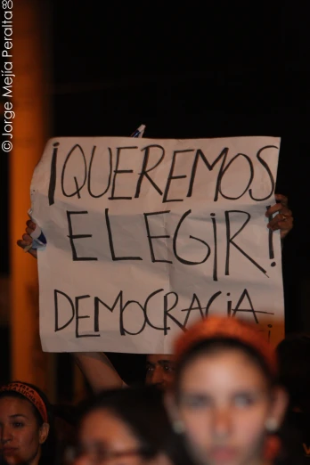 a man holding up a sign that reads i comemos elegir denocacia