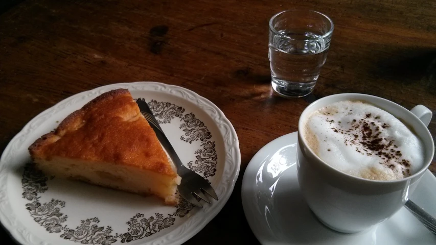 there is a plate with a piece of cake next to a cup of coffee