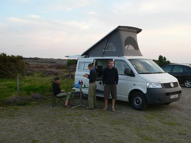two men with small children in front of a camper van