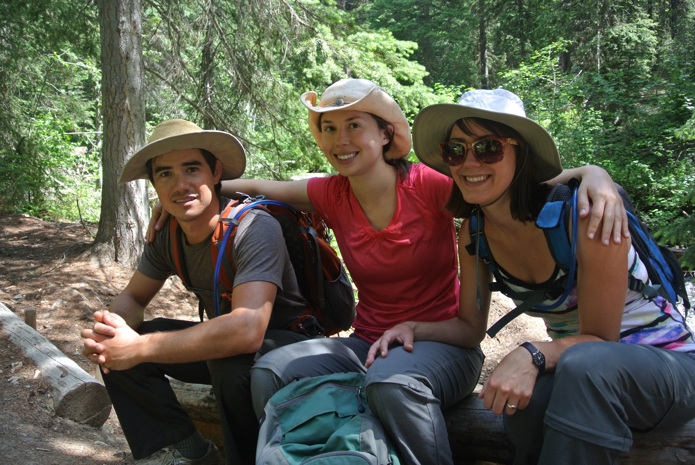 three people posing for the camera, with their back pack attached to their backs