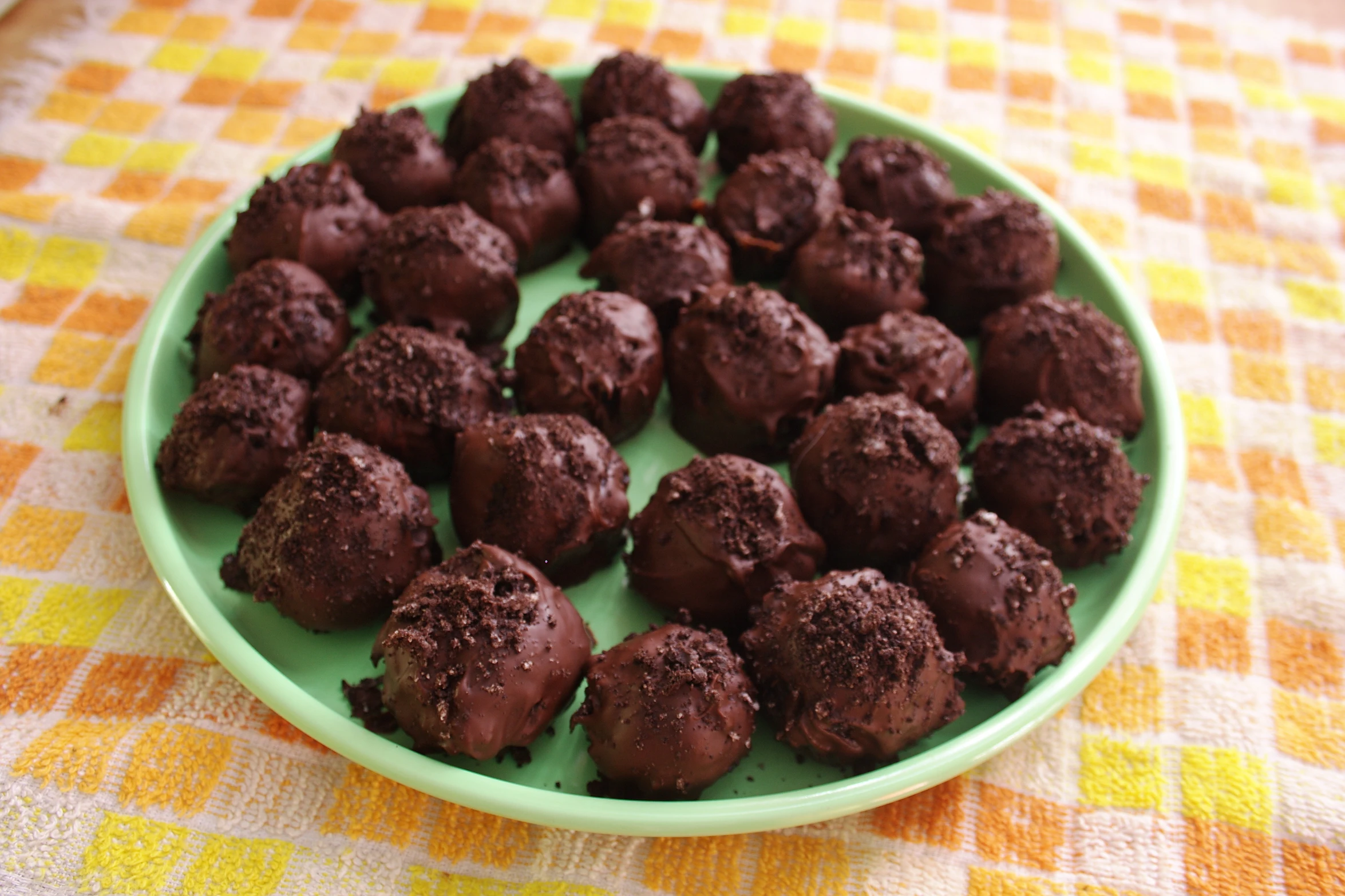 a green plate has chocolate truffles on it