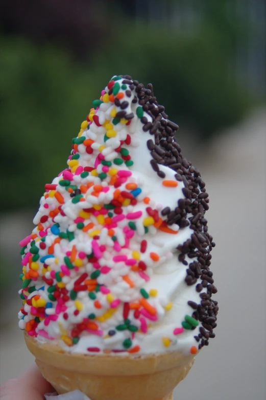 someone is holding an ice cream cone filled with sprinkles