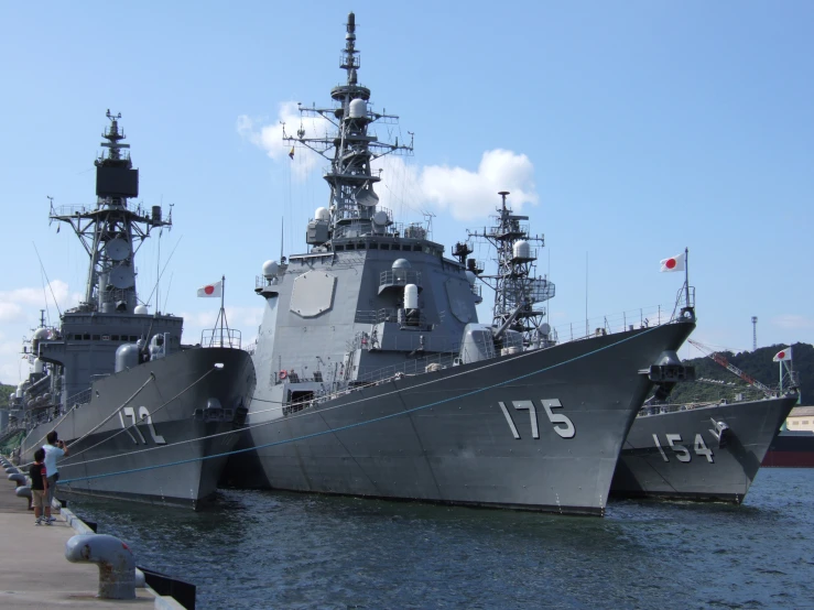 several navy ships in dock with blue sky