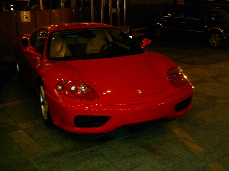 a ferrari sits on the sidewalk while the city street is dark