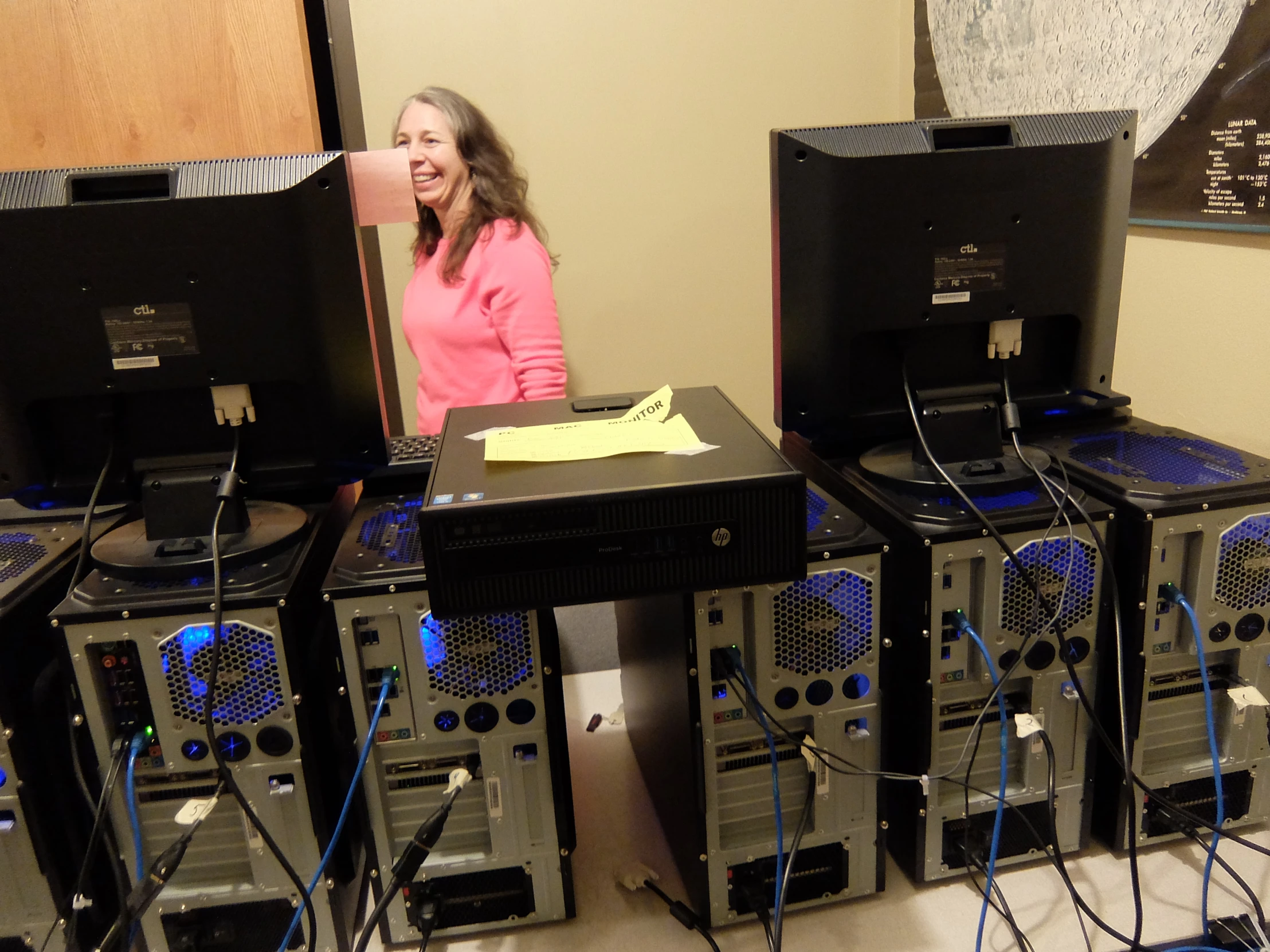 a woman standing behind a large number of computers