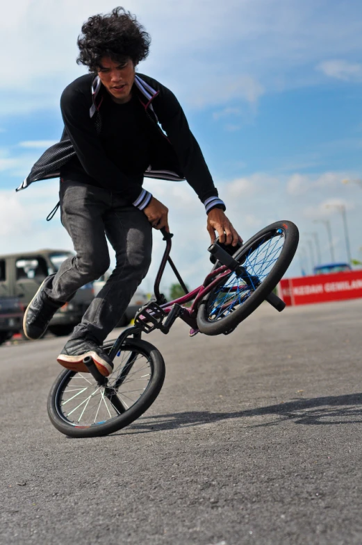 a man with a jacket rides an unicycle while holding the wheel up