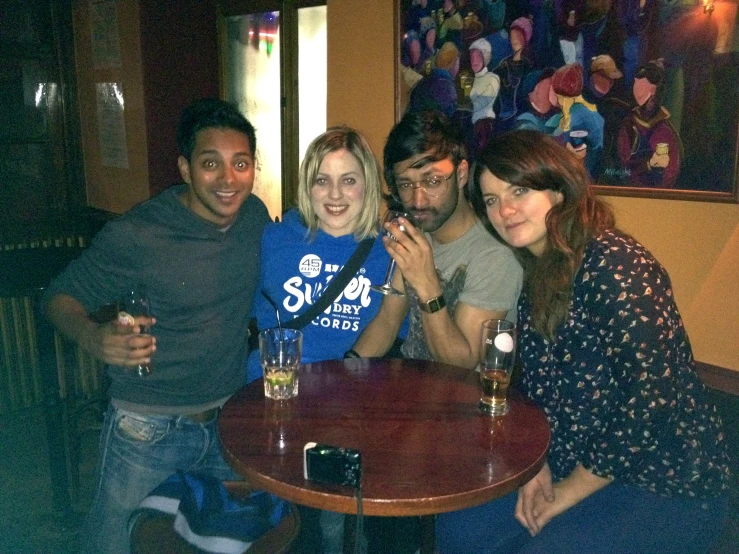 a group of people sitting around a table posing for a picture