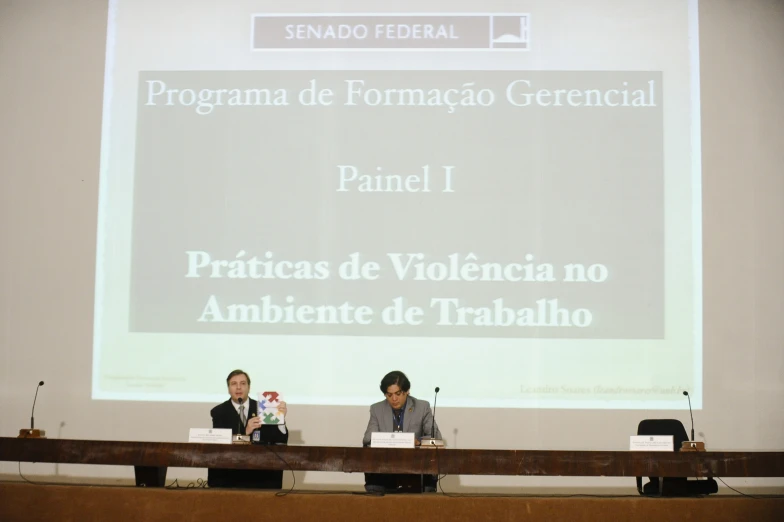 the three people are sitting on a long table