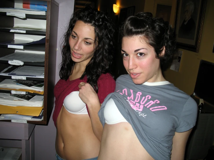 two women that are standing up in front of some papers