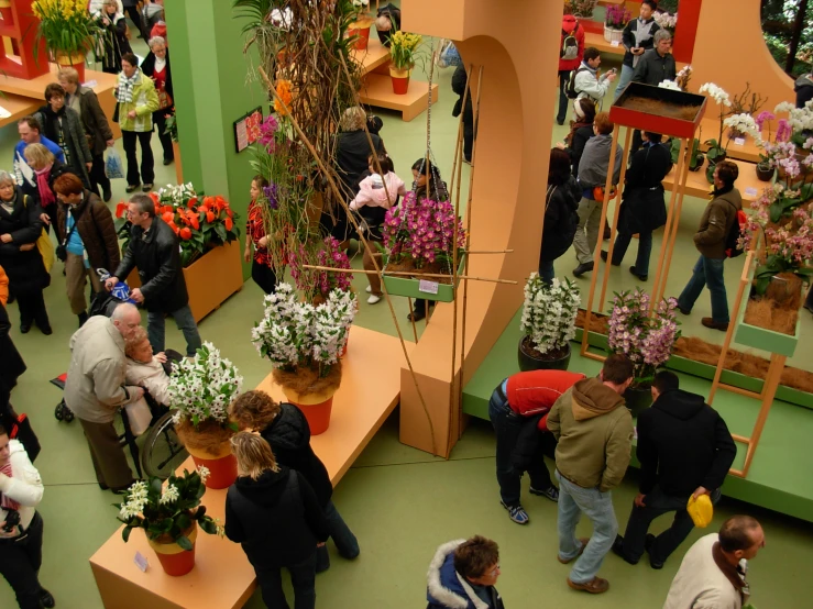 a large group of people in a large room with many plants