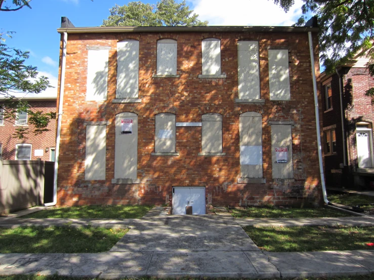 large brown brick building with white shutters and several windows