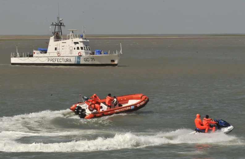 people in lifejackes on small boats and a small boat near the shore