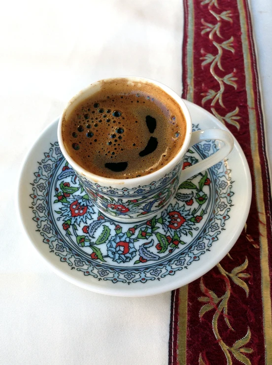 coffee with a smiley face drawn on the inside is sitting on a plate