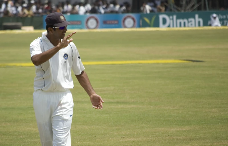 a man standing in the middle of a field holding his finger up to his mouth