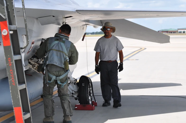 two men in camouflage gear prepare to load luggage onto an airplane