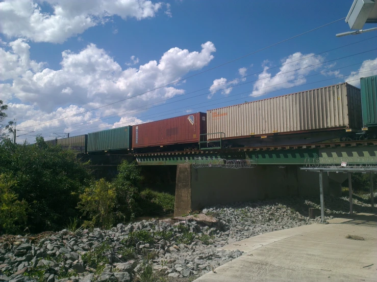 train on elevated track passing below clouds in the sky