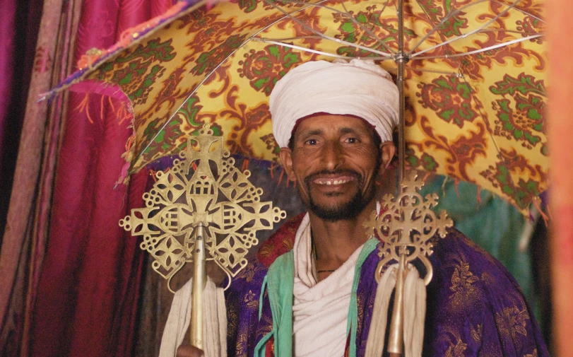 a man in turban holds two ornate items