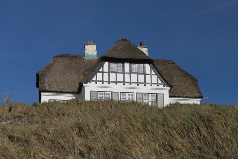 a large white house with a grass covered roof