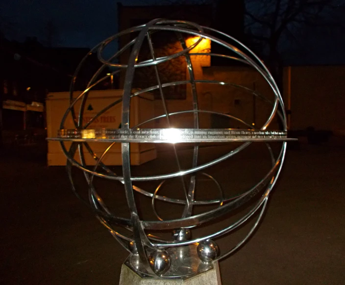 an artistic metal ball and sphere on the side of a street