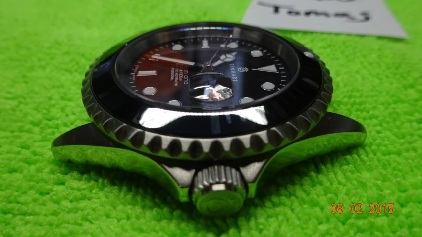 a stainless steel watch on green fabric with a tag in the background