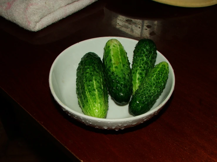 a white bowl of cucumbers on a table