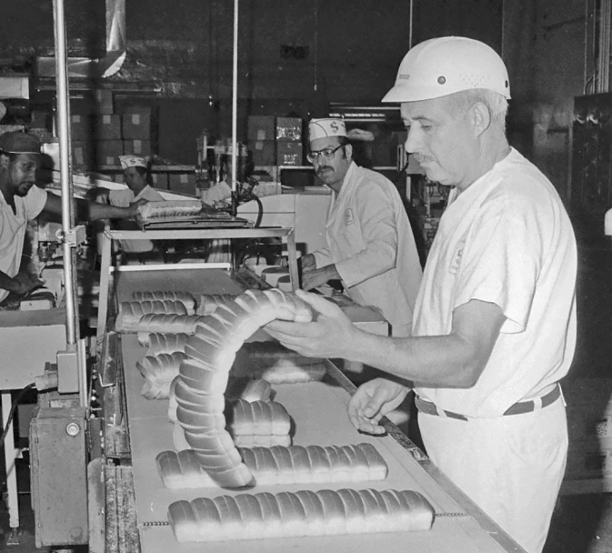 men working on machinery inside a factory with workers behind them