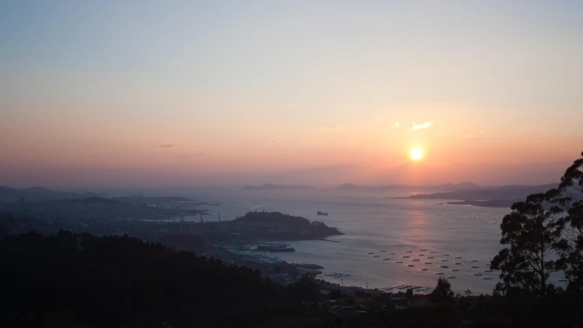 the sun sets over a bay surrounded by trees