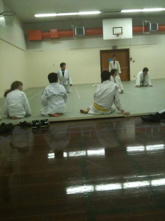 people sitting on the ground watching a man performing a karate sequence
