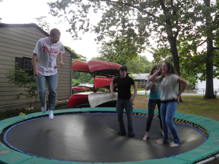 a man standing on a trampoline while three girls stand