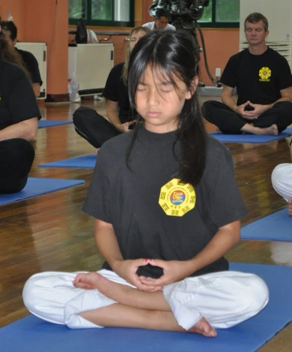 a small child sitting in the lotus on blue mats