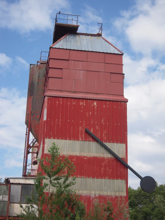 an old red and white barn with a large crane on top