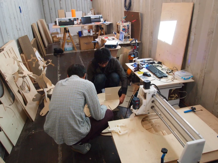 two men working in a workshop with a machine