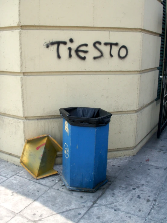 a blue trash can and black trash cans sit outside of a building