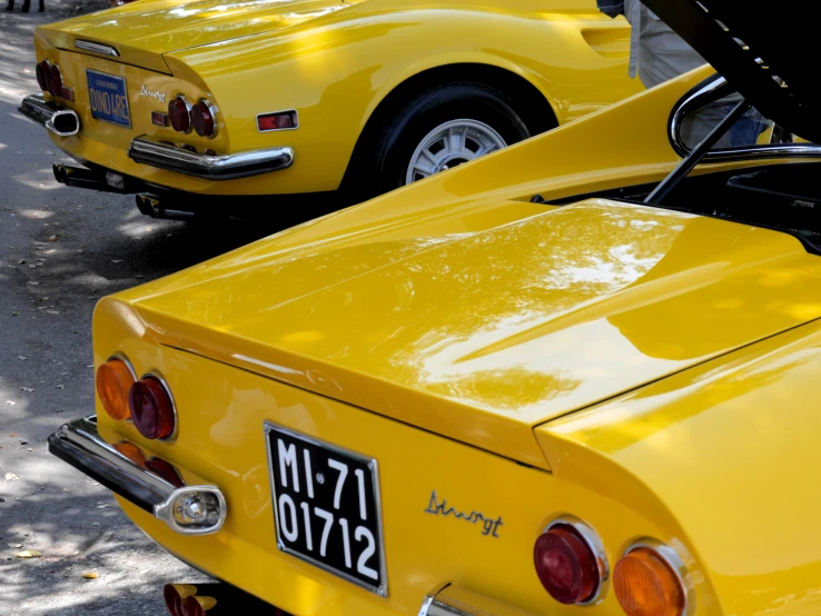 two yellow classic sports cars with a license plate