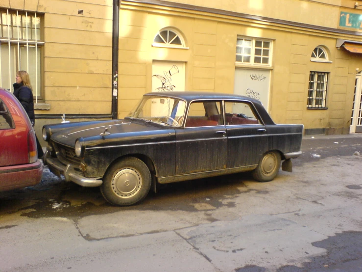 a classic car is parked by a curb in a city