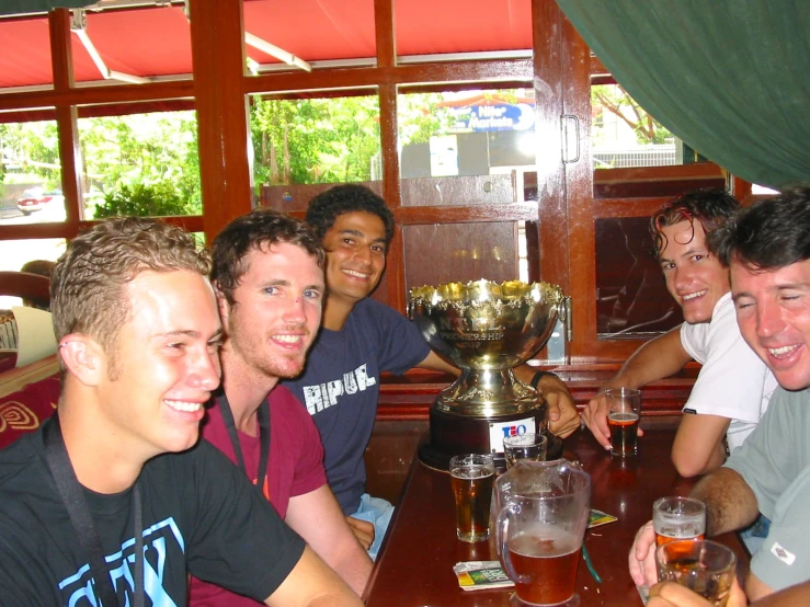 four men are sitting at a table with beer